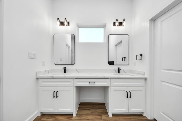 bathroom with double vanity, wood finished floors, a sink, and baseboards