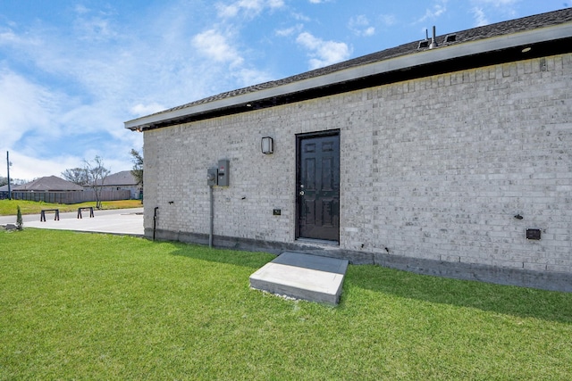 view of exterior entry featuring a yard and brick siding