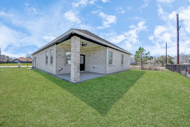 rear view of property featuring a ceiling fan, brick siding, a lawn, and a patio