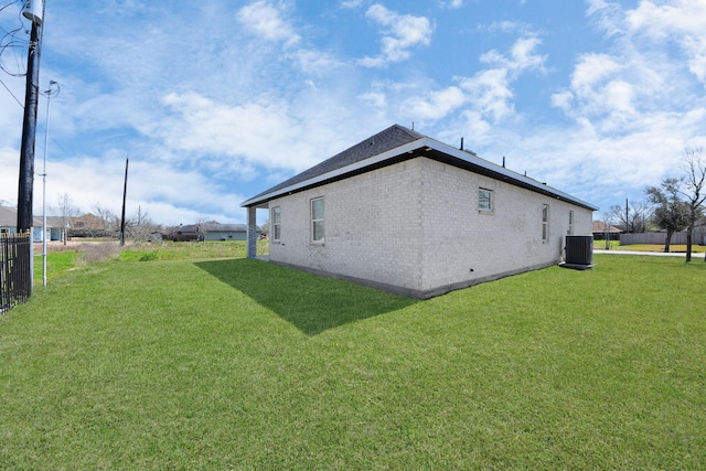 view of home's exterior with brick siding, a lawn, fence, and central air condition unit