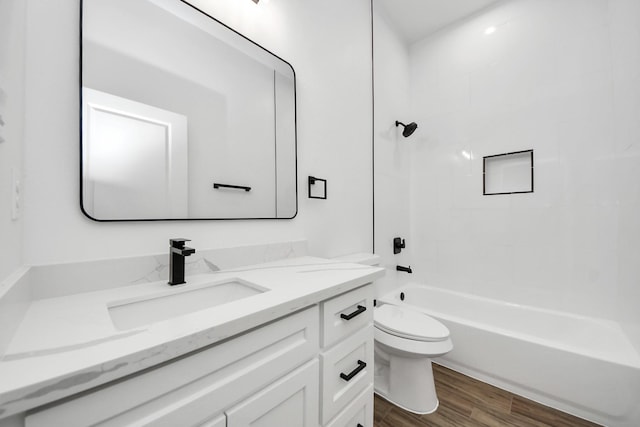 bathroom featuring toilet,  shower combination, wood finished floors, and vanity