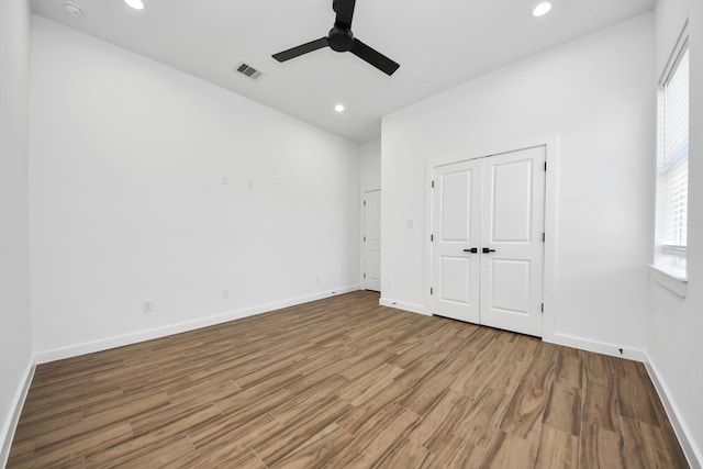 unfurnished bedroom featuring baseboards, wood finished floors, visible vents, and recessed lighting