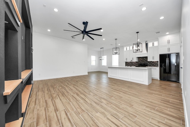 kitchen with open floor plan, light countertops, backsplash, and black fridge with ice dispenser