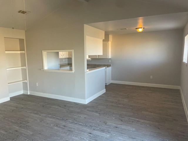 empty room featuring lofted ceiling, dark wood finished floors, visible vents, and baseboards