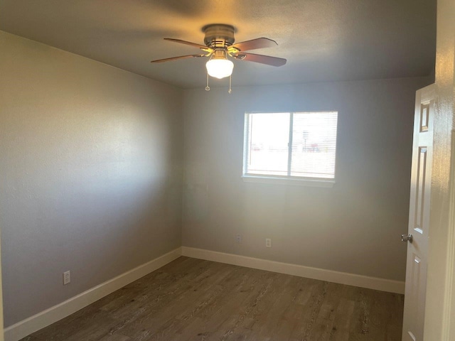 spare room with a ceiling fan, baseboards, and dark wood-type flooring