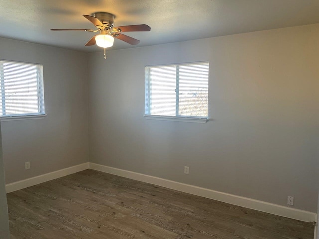 unfurnished room with dark wood-style flooring, ceiling fan, and baseboards