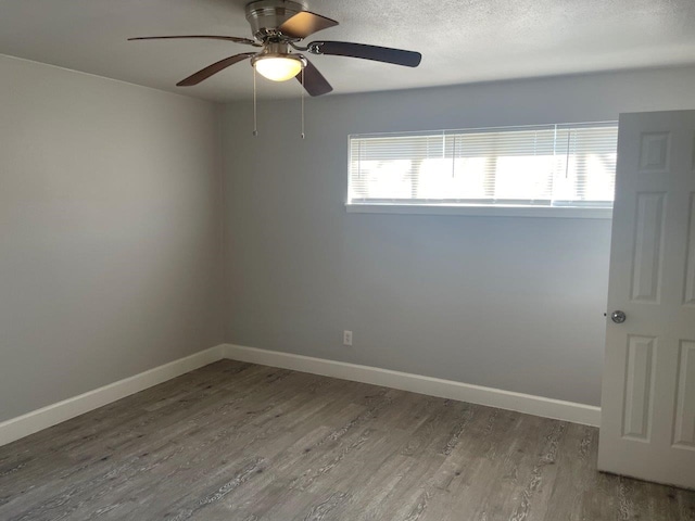 empty room with a ceiling fan, a textured ceiling, baseboards, and wood finished floors