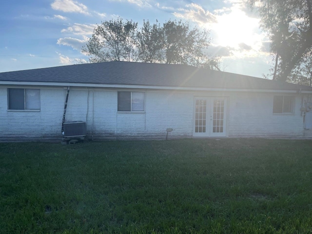 back of property featuring a yard, french doors, roof with shingles, and brick siding