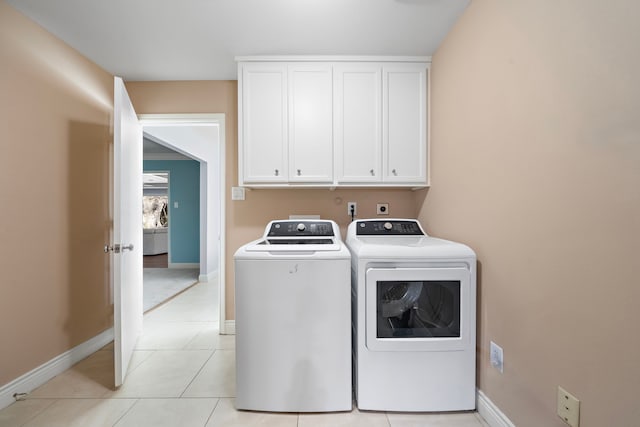 laundry room with baseboards, light tile patterned floors, cabinet space, and washer and dryer