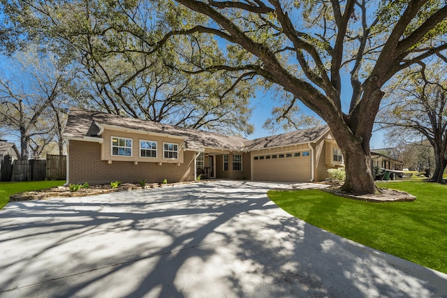 view of front facade with brick siding, concrete driveway, a front yard, fence, and a garage