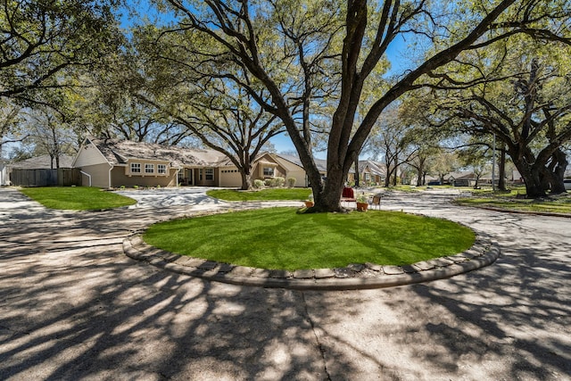 view of property's community with driveway, fence, and a lawn