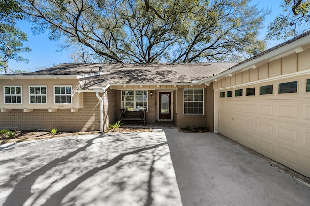 property entrance with a garage, concrete driveway, brick siding, and board and batten siding