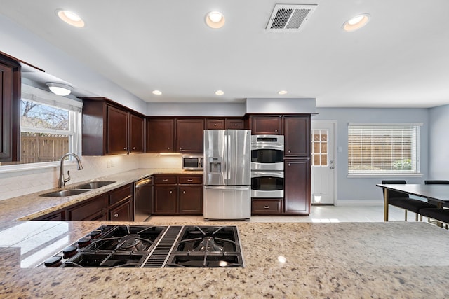 kitchen featuring visible vents, decorative backsplash, a sink, stainless steel appliances, and a wealth of natural light