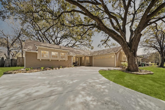 view of front of house with driveway, an attached garage, fence, a front lawn, and brick siding