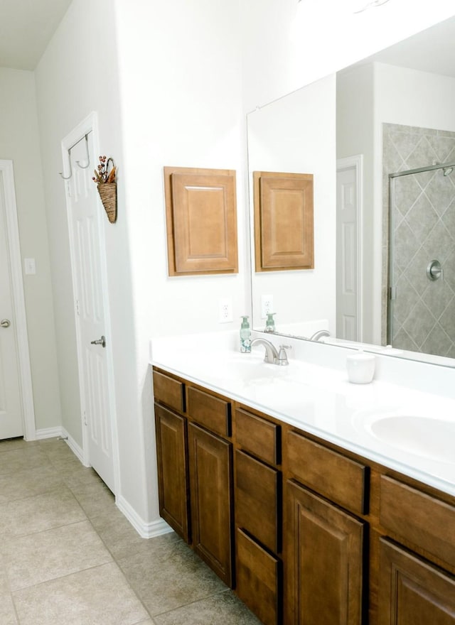 full bathroom with double vanity, a stall shower, baseboards, tile patterned flooring, and a sink