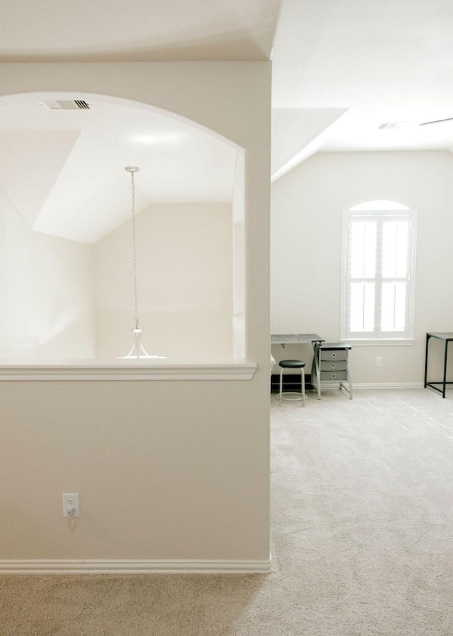 corridor featuring lofted ceiling, carpet, visible vents, and baseboards