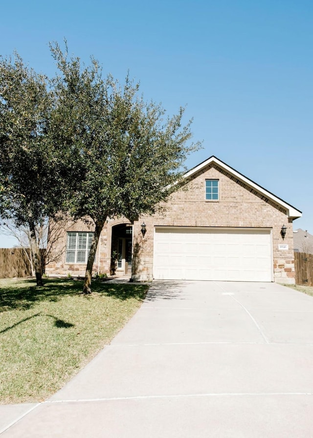 view of front of house featuring driveway, an attached garage, fence, a front lawn, and brick siding