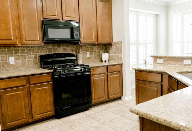 kitchen featuring brown cabinets, light tile patterned floors, backsplash, ornamental molding, and black appliances