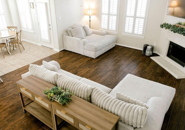 living room with a high end fireplace, baseboards, and wood finished floors