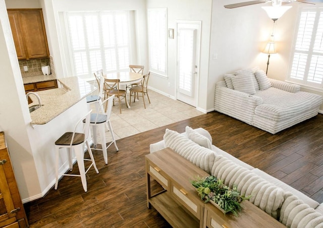 living area featuring light wood-style floors, ceiling fan, and baseboards