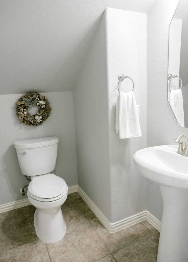 bathroom with lofted ceiling, tile patterned floors, toilet, and baseboards