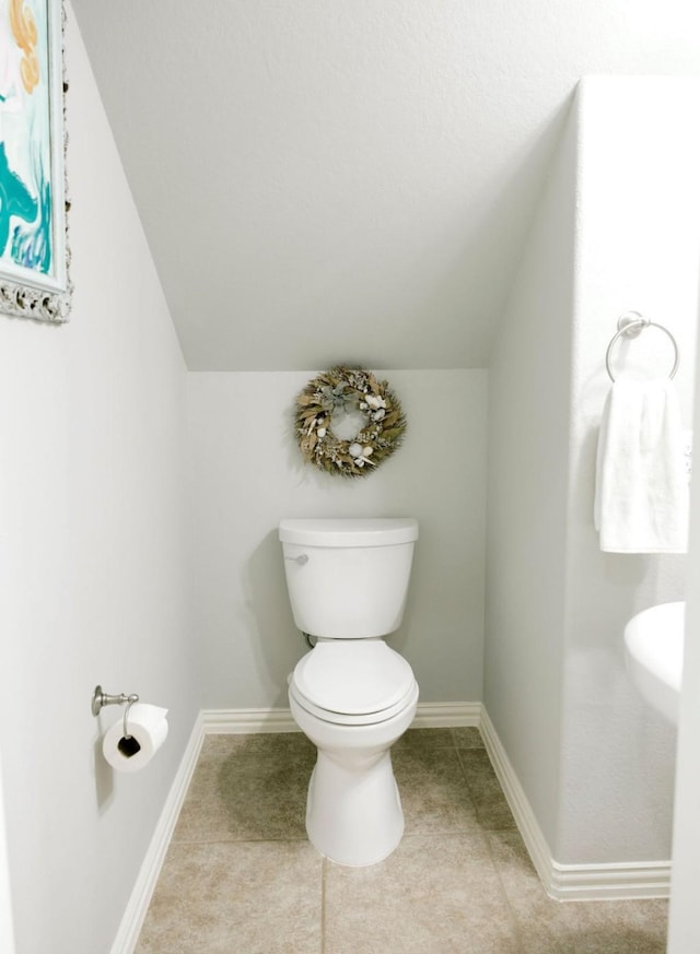 bathroom with vaulted ceiling, tile patterned flooring, toilet, and baseboards