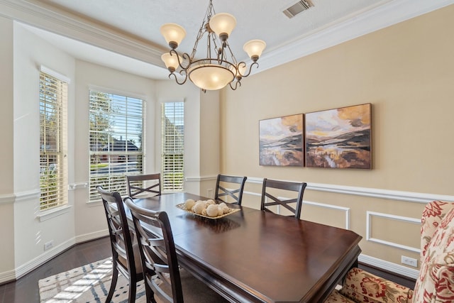 dining space featuring baseboards, visible vents, wood finished floors, an inviting chandelier, and crown molding