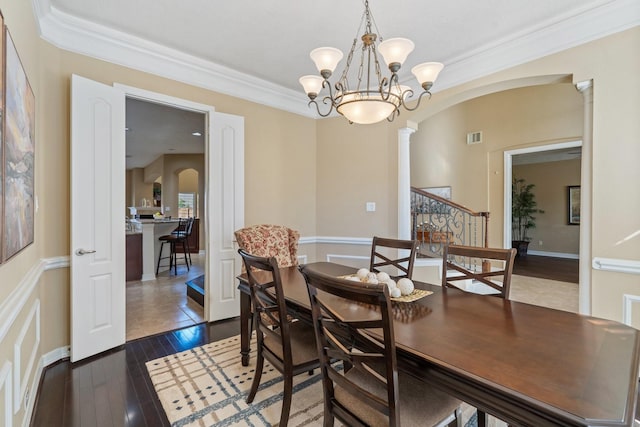 dining space featuring arched walkways, crown molding, visible vents, dark wood-type flooring, and ornate columns