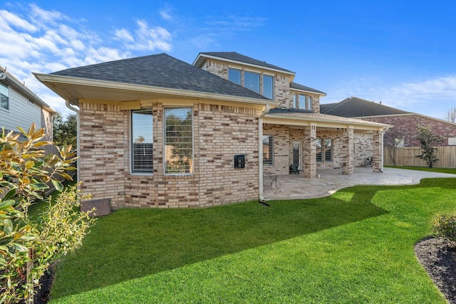 back of house with brick siding, a lawn, a patio area, and fence