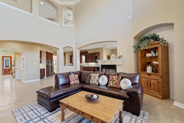 living room featuring light tile patterned floors, a fireplace, arched walkways, and baseboards