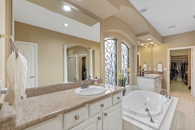 full bath featuring a jetted tub, tile patterned flooring, a sink, and decorative columns