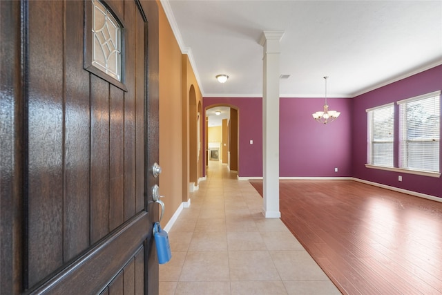 entryway with arched walkways, ornamental molding, a notable chandelier, and baseboards