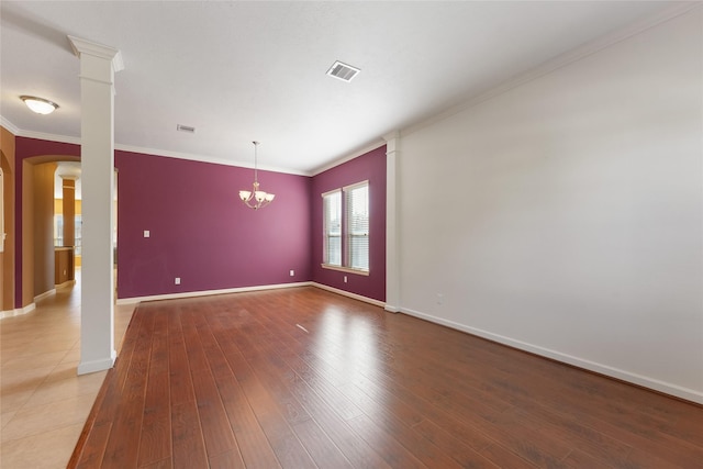 unfurnished room with ornate columns, visible vents, ornamental molding, wood finished floors, and baseboards