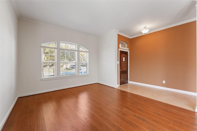 unfurnished room with ornamental molding, baseboards, and wood finished floors