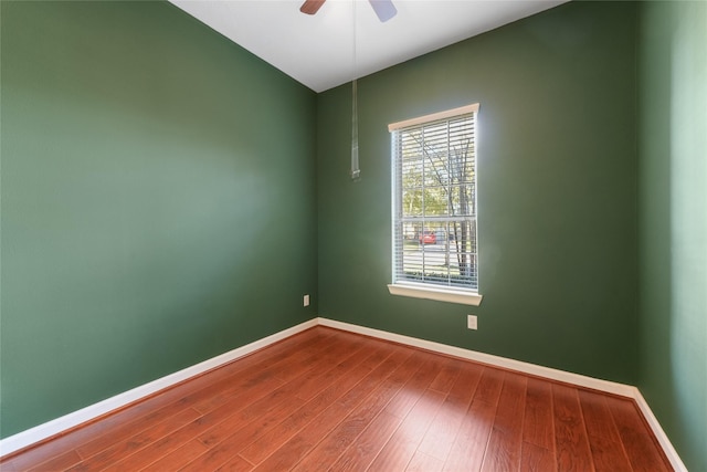 unfurnished room featuring a ceiling fan, dark wood finished floors, and baseboards