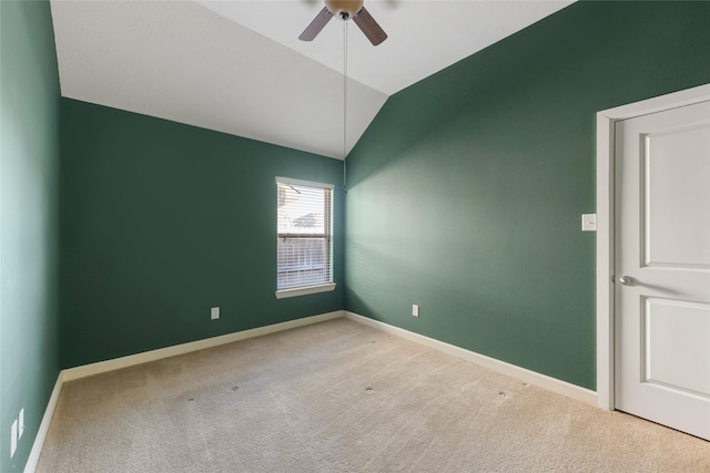 empty room with carpet flooring, vaulted ceiling, baseboards, and ceiling fan