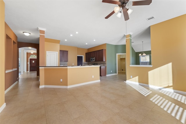 kitchen featuring arched walkways, visible vents, stainless steel microwave, open floor plan, and a kitchen island