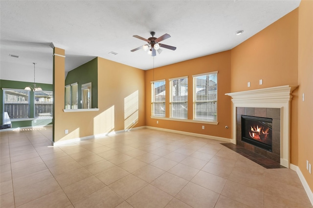 unfurnished living room featuring a tile fireplace, ceiling fan, baseboards, and light tile patterned floors