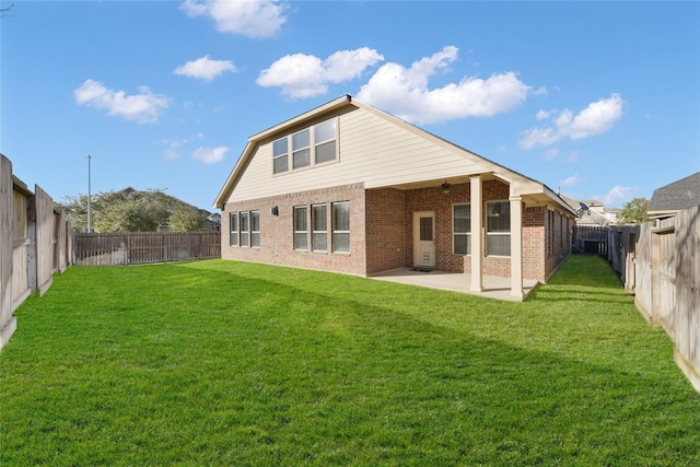 back of house with a fenced backyard, brick siding, a ceiling fan, a lawn, and a patio area