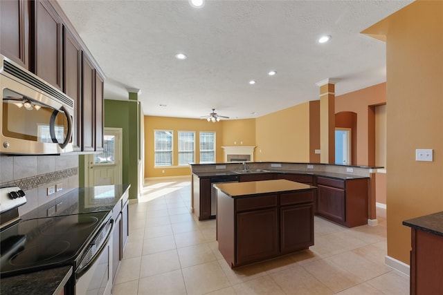 kitchen with stainless steel appliances, a fireplace, a sink, tasteful backsplash, and a center island with sink