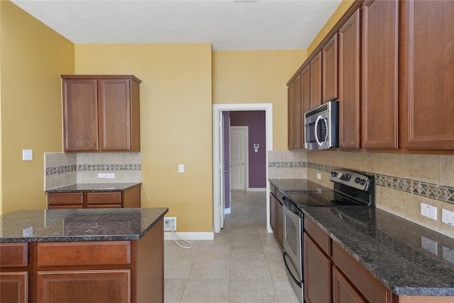 kitchen with light tile patterned floors, stainless steel appliances, tasteful backsplash, dark stone counters, and baseboards