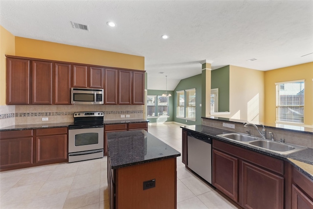 kitchen with appliances with stainless steel finishes, visible vents, a sink, and tasteful backsplash