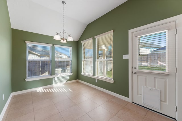 unfurnished dining area with a chandelier, tile patterned flooring, vaulted ceiling, and baseboards