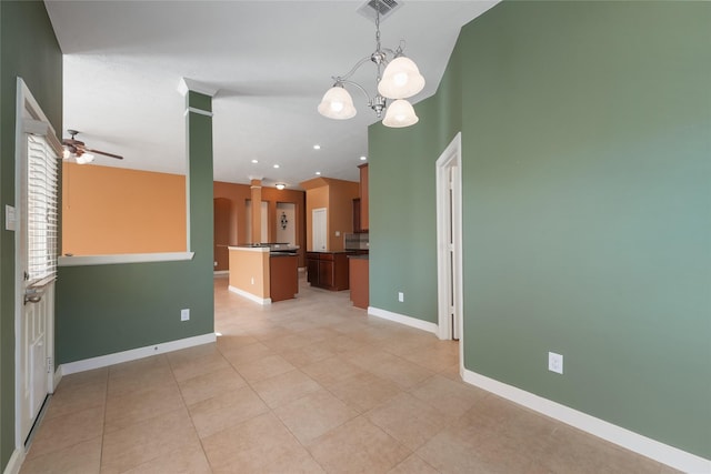 empty room featuring ceiling fan with notable chandelier, light tile patterned flooring, visible vents, and baseboards