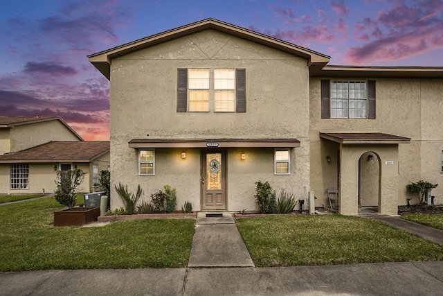 view of front facade with a lawn and stucco siding