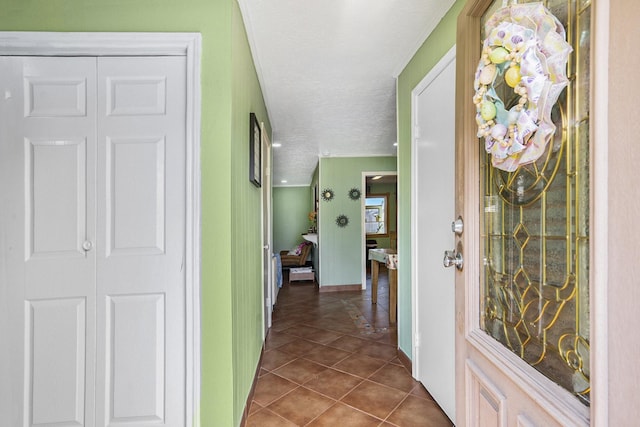 hallway featuring a textured ceiling, dark tile patterned floors, and baseboards