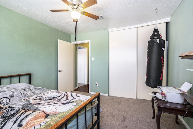 carpeted bedroom with a closet, visible vents, ceiling fan, and a textured ceiling