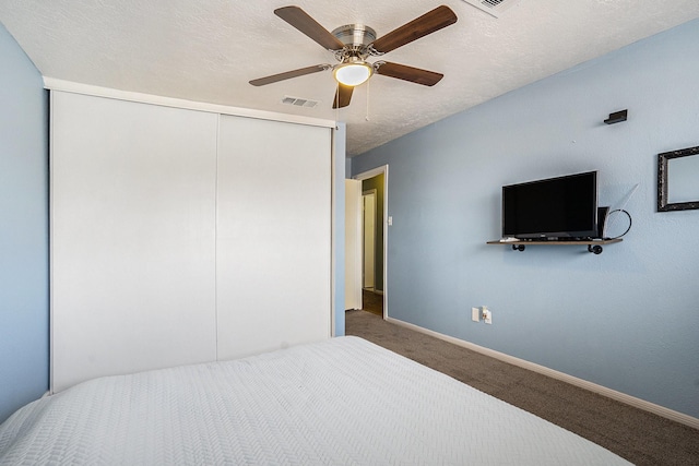 carpeted bedroom featuring a closet, visible vents, a ceiling fan, a textured ceiling, and baseboards