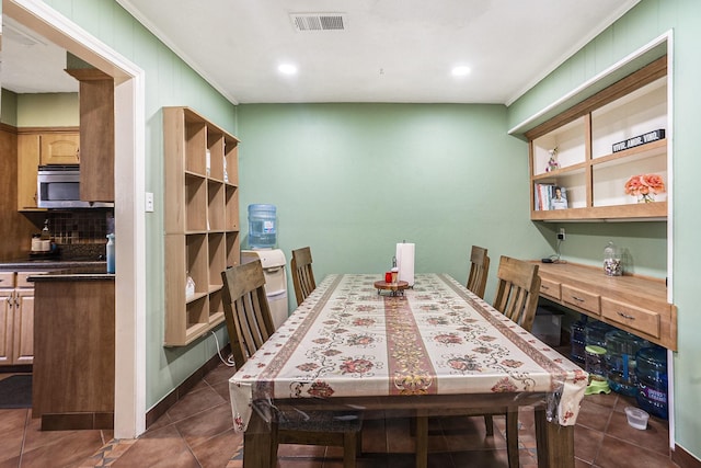 dining room featuring dark tile patterned flooring, visible vents, and crown molding