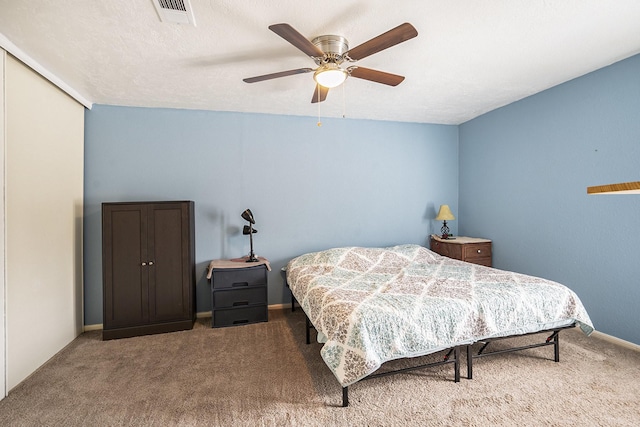 carpeted bedroom with a ceiling fan, visible vents, a textured ceiling, and baseboards